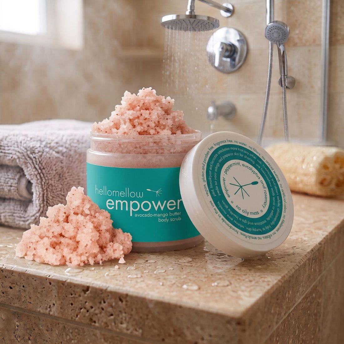 empower body scrub on a shower ledge beside a folded towel