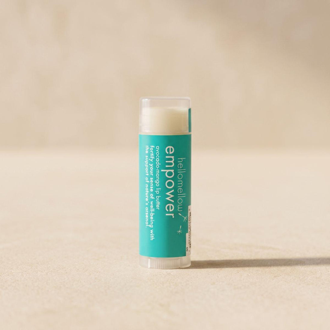 empower lip butter standing front-facing on a warm neutral surface