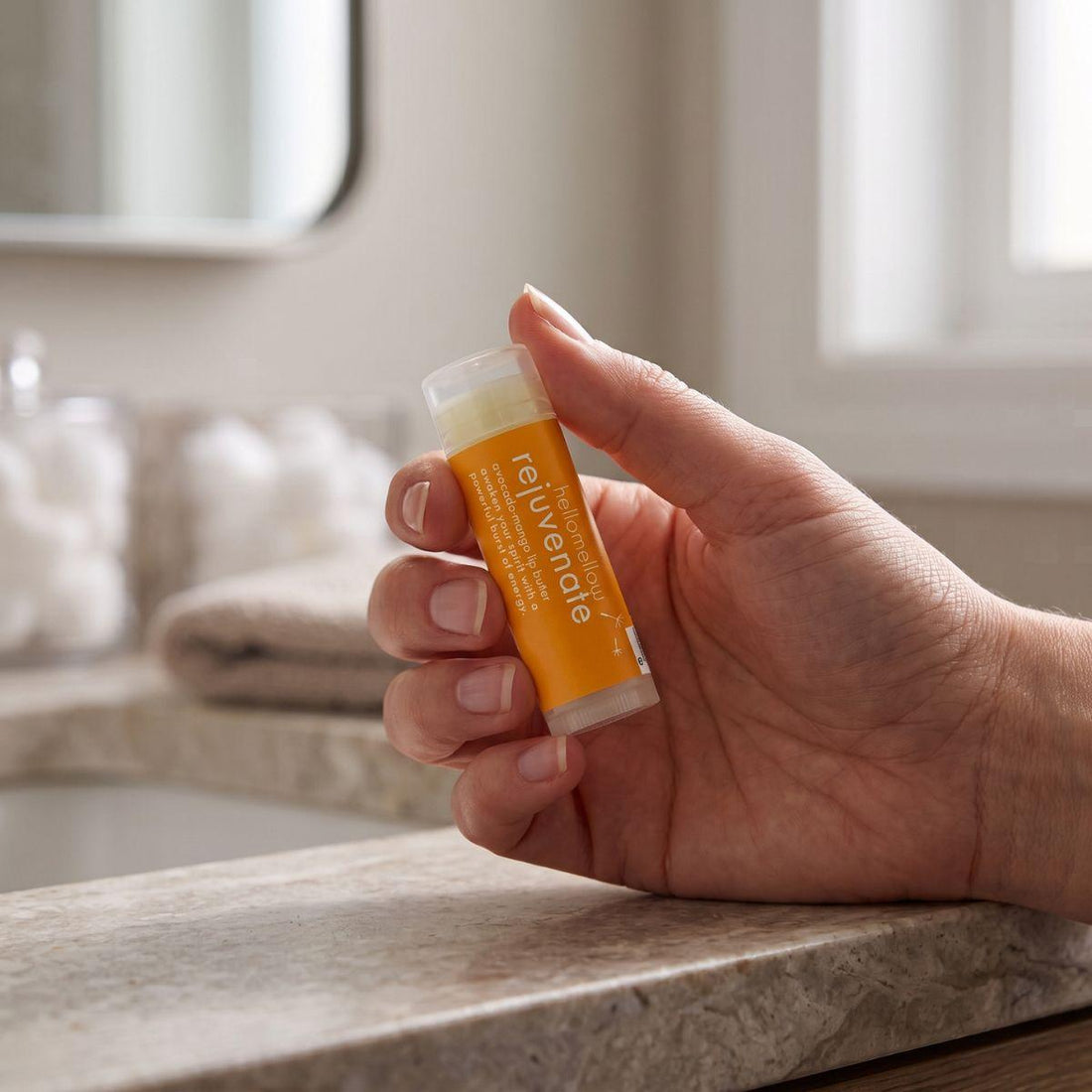 adult hand holding the rejuvenate lip butter to show its everyday size