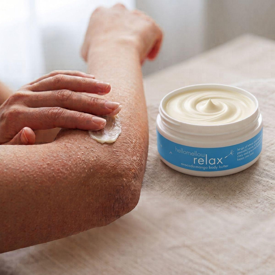 hands applying relax body butter to a dry elbow for targeted moisture