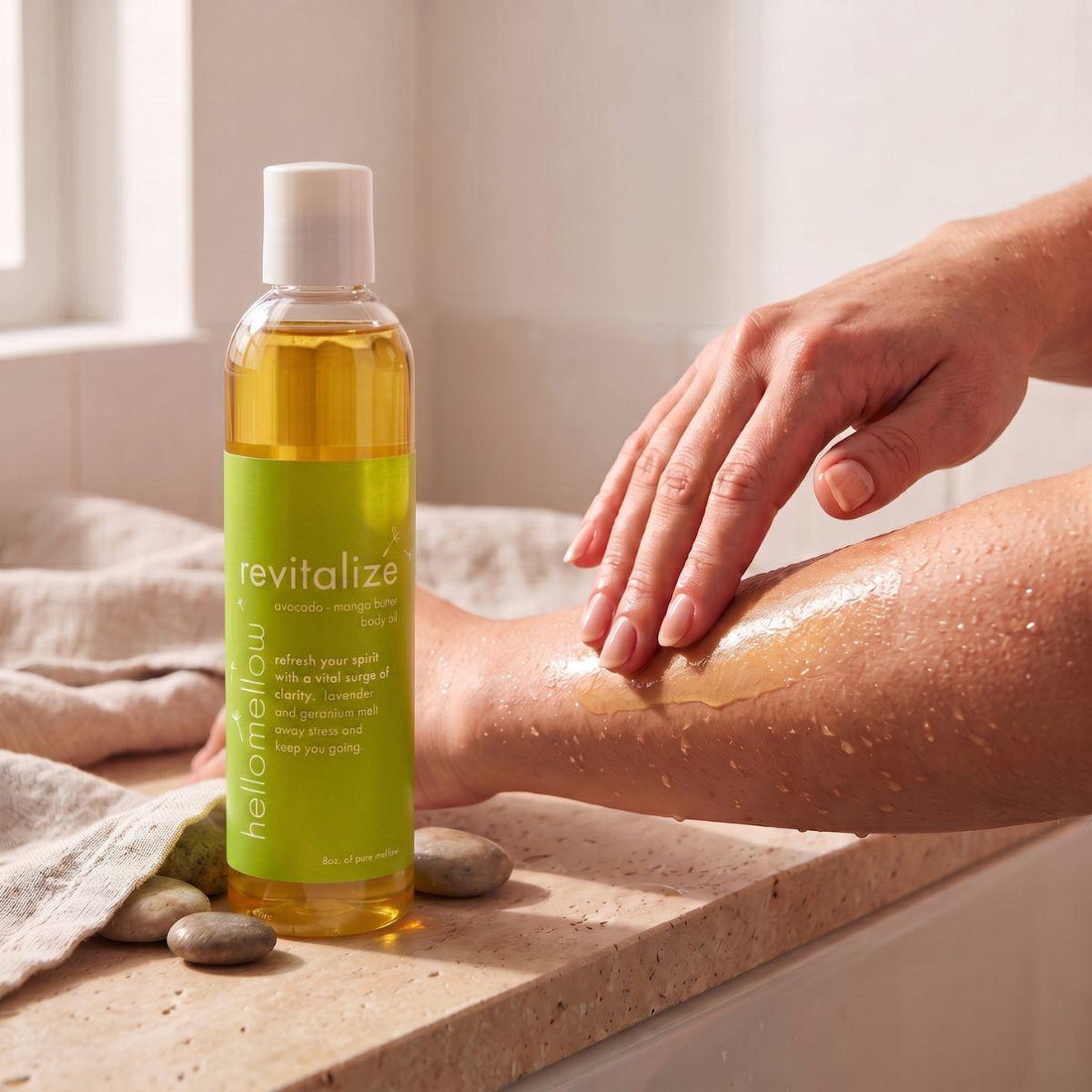 hands smoothing revitalize body oil onto damp skin after a shower