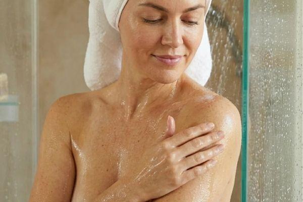 woman applying hellomellow body oil after showering
