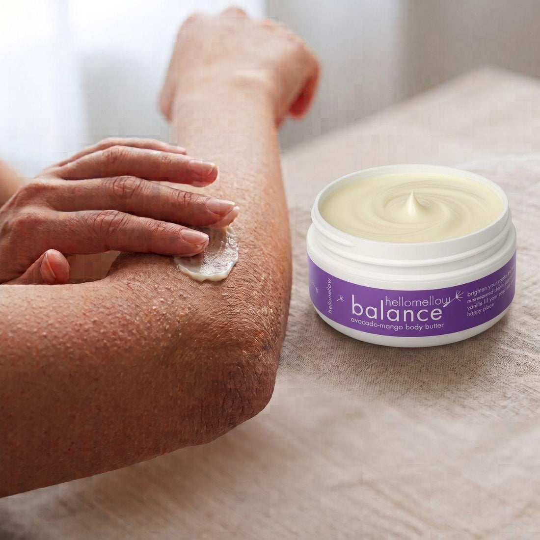 hands applying balance body butter to a dry elbow for targeted moisture