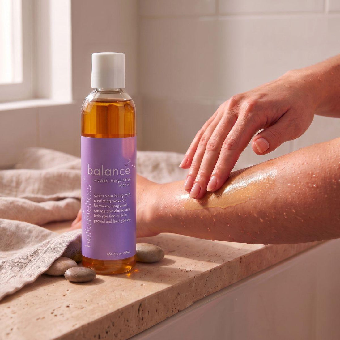 hands smoothing balance body oil onto damp skin after a shower