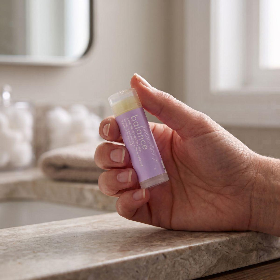 adult hand holding the balance lip butter to show its everyday size