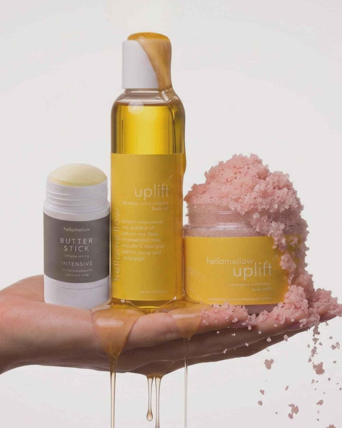 woman's hand holding hellomellow body scrub and body oil uplift and butter stick 