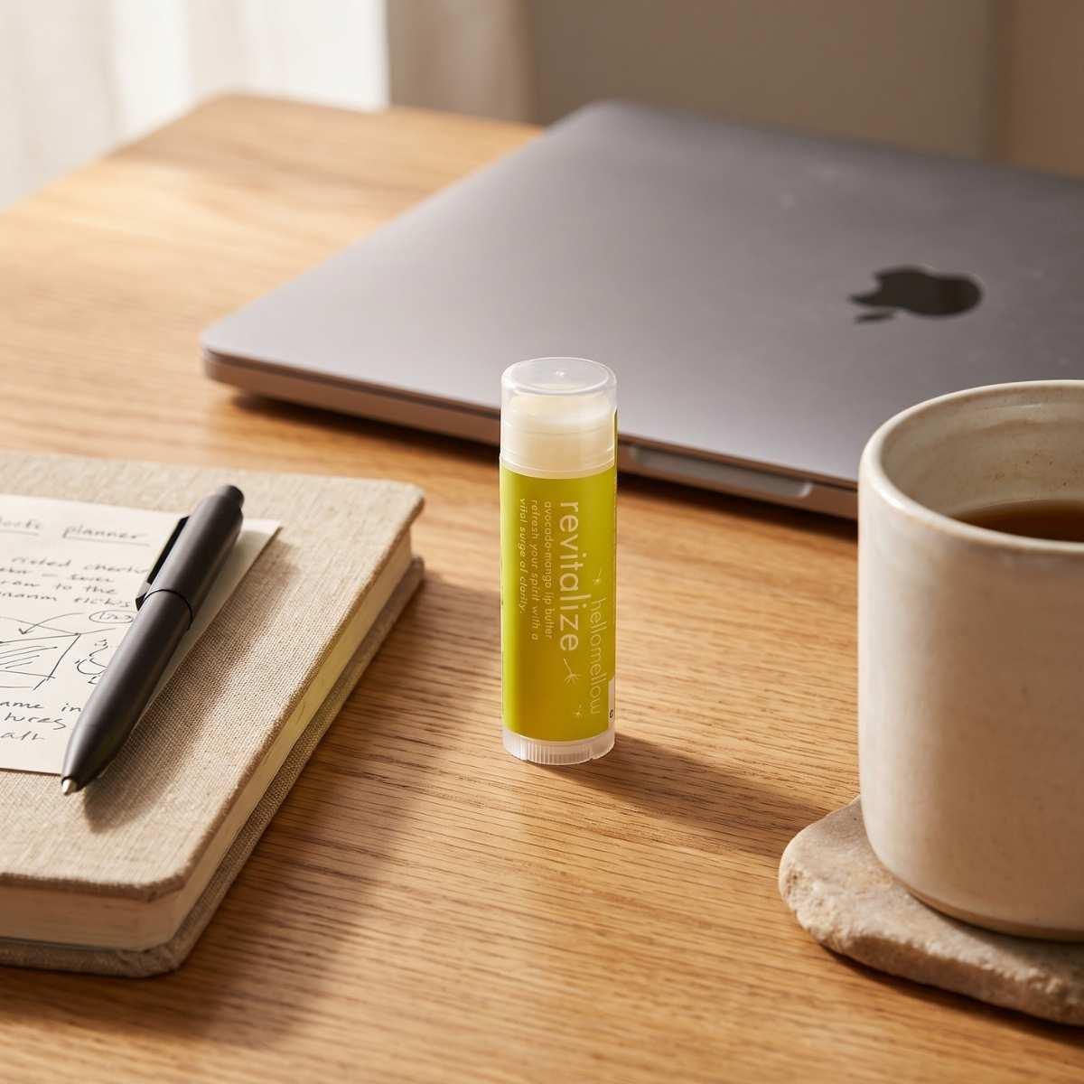 hellomellow revitalize lip butter tube on a warm desk setup.