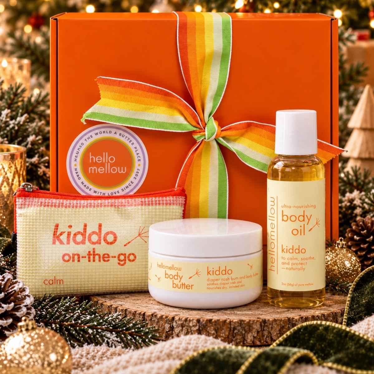 hellomellow kiddo on-the-go body oil, body butter and travel pouch displayed with an orange holiday gift box.