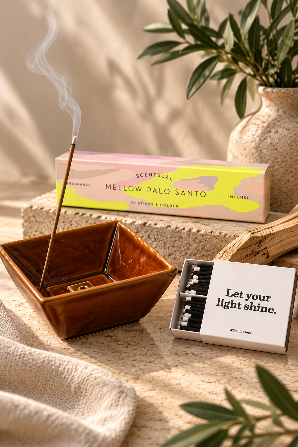 mellow palo santo incense with a brown ceramic bowl and inspirational matches on a warm neutral surface