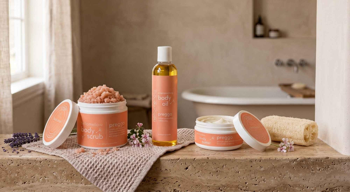 full-size preggo body scrub, body oil and body butter arranged together in a warm bathroom.