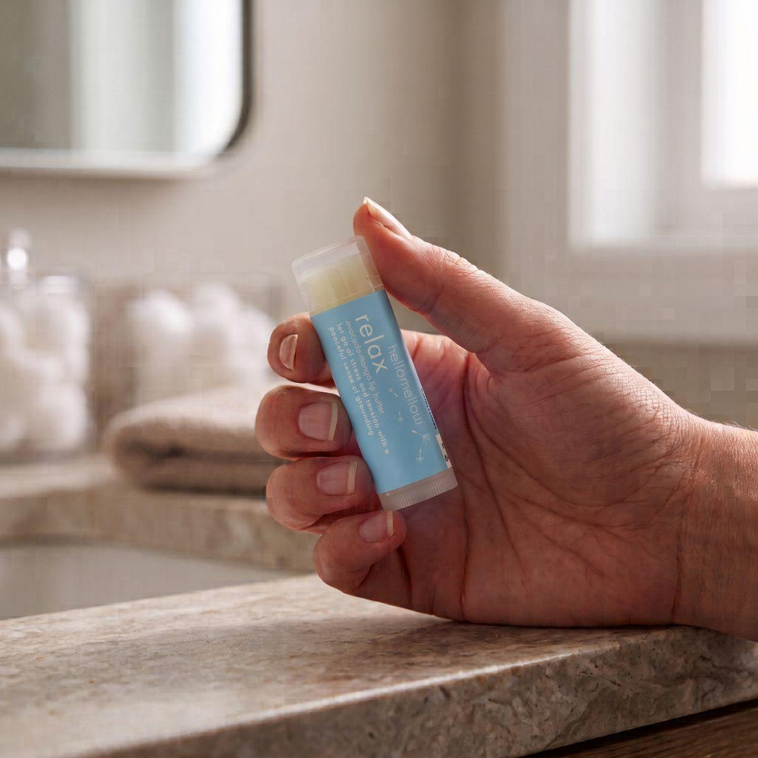 adult hand holding the relax lip butter to show its everyday size