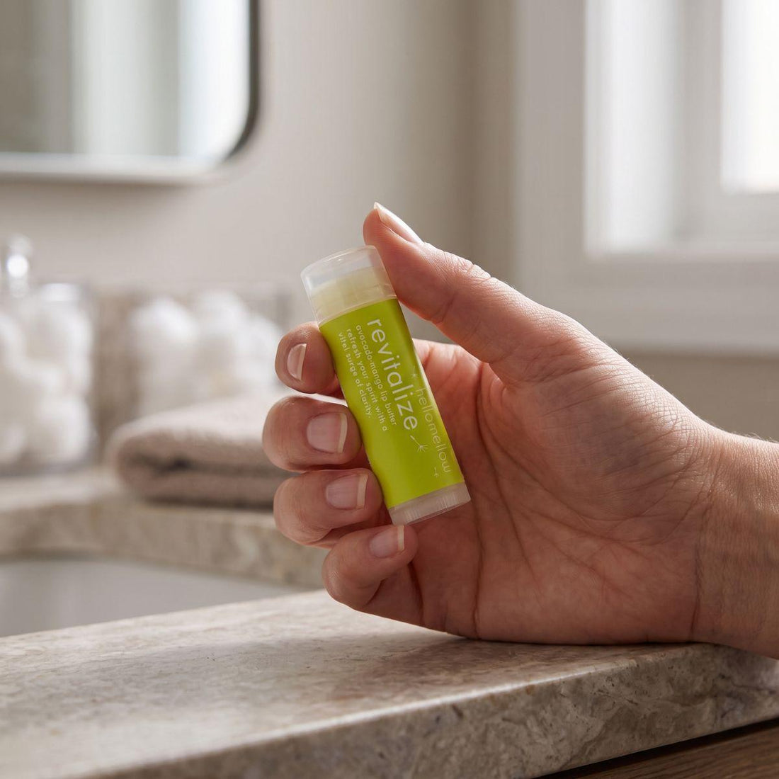 adult hand holding the revitalize lip butter to show its everyday size