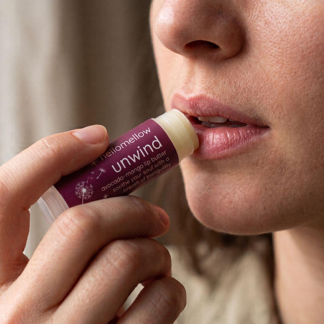 unwind lip butter being applied naturally to lips in soft daylight