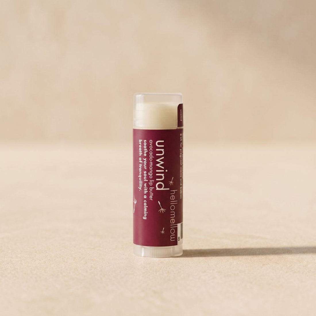 unwind lip butter standing front-facing on a warm neutral surface
