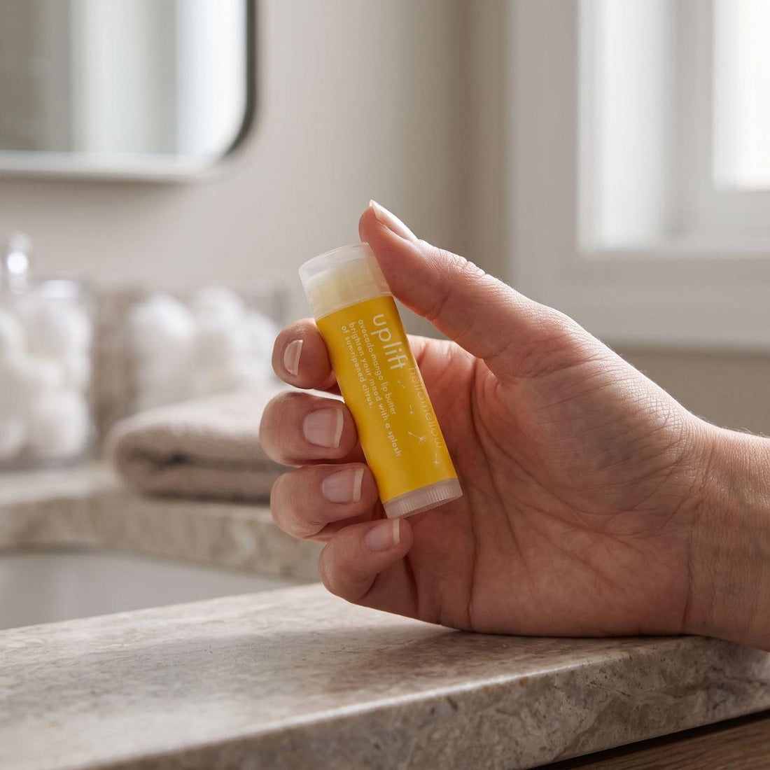 adult hand holding the uplift lip butter to show its everyday size